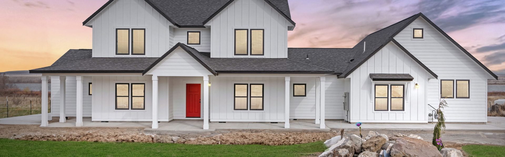 Photo at dusk of a modern farmhouse home with a red door